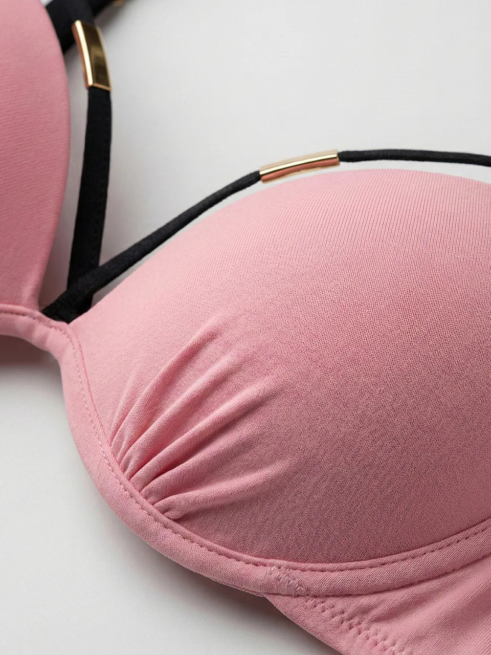 Nahaufnahme des hellrosa Bikini-Oberteils mit gerafftem Stoff und goldfarbenem Zierelement
