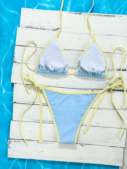 Hellblauer Triangle Bikini mit gelben Bindebändern flach auf weißem Holz am Pool fotografiert